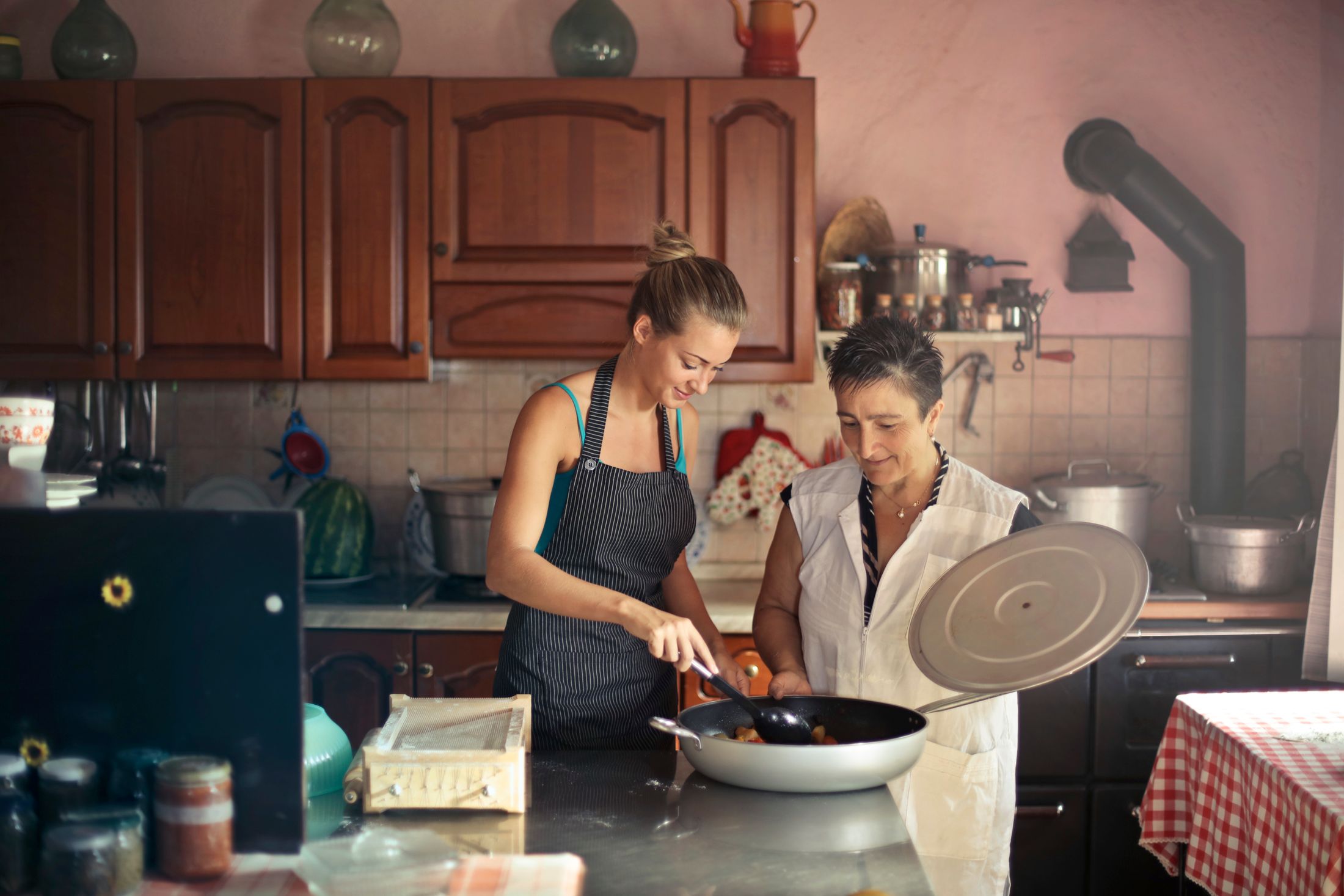 Dos mujeres comparten la preparación de una comida en casa; fotografía ilustrativa